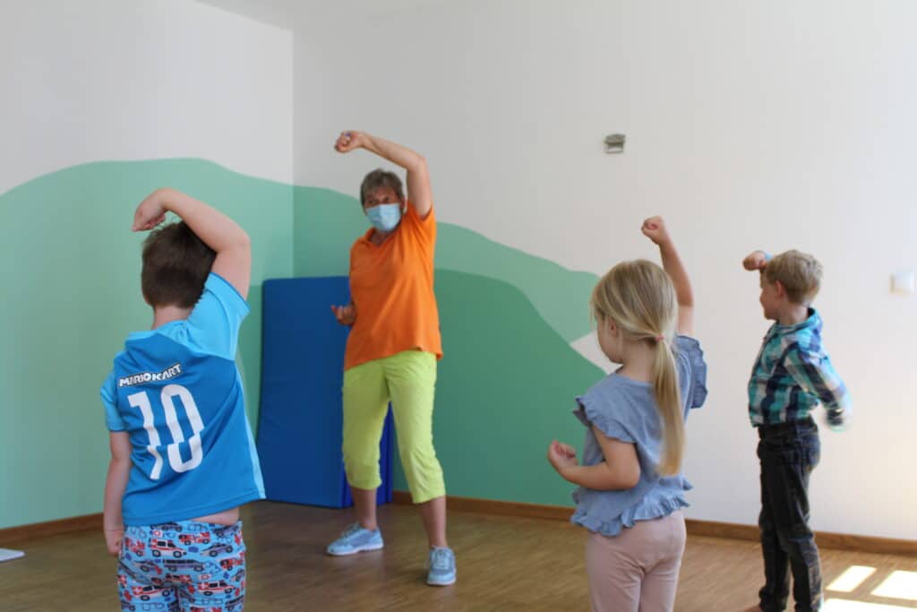 Kinder stehen vor der Selbstbehauptungstrainerin im Halbkreis und reißen abwehrend die Arme hoch.